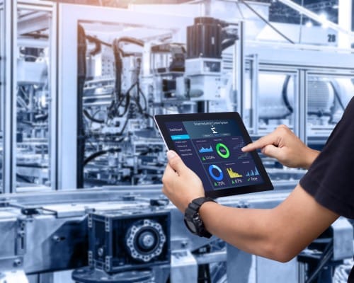 Intelligent industrial control idea. Hands holding a tablet against a hazy automation machine in the backdrop