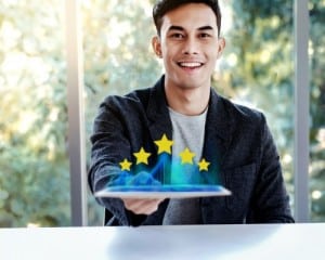 Happy Young Man Sitting at the Desk and presenting his Five Star Rating. Customer Experiences Concept