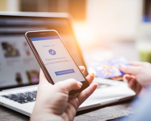 Close up view of female hands holding mobile and making a payment using credit card